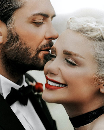 man whispering in smiling woman's ear
